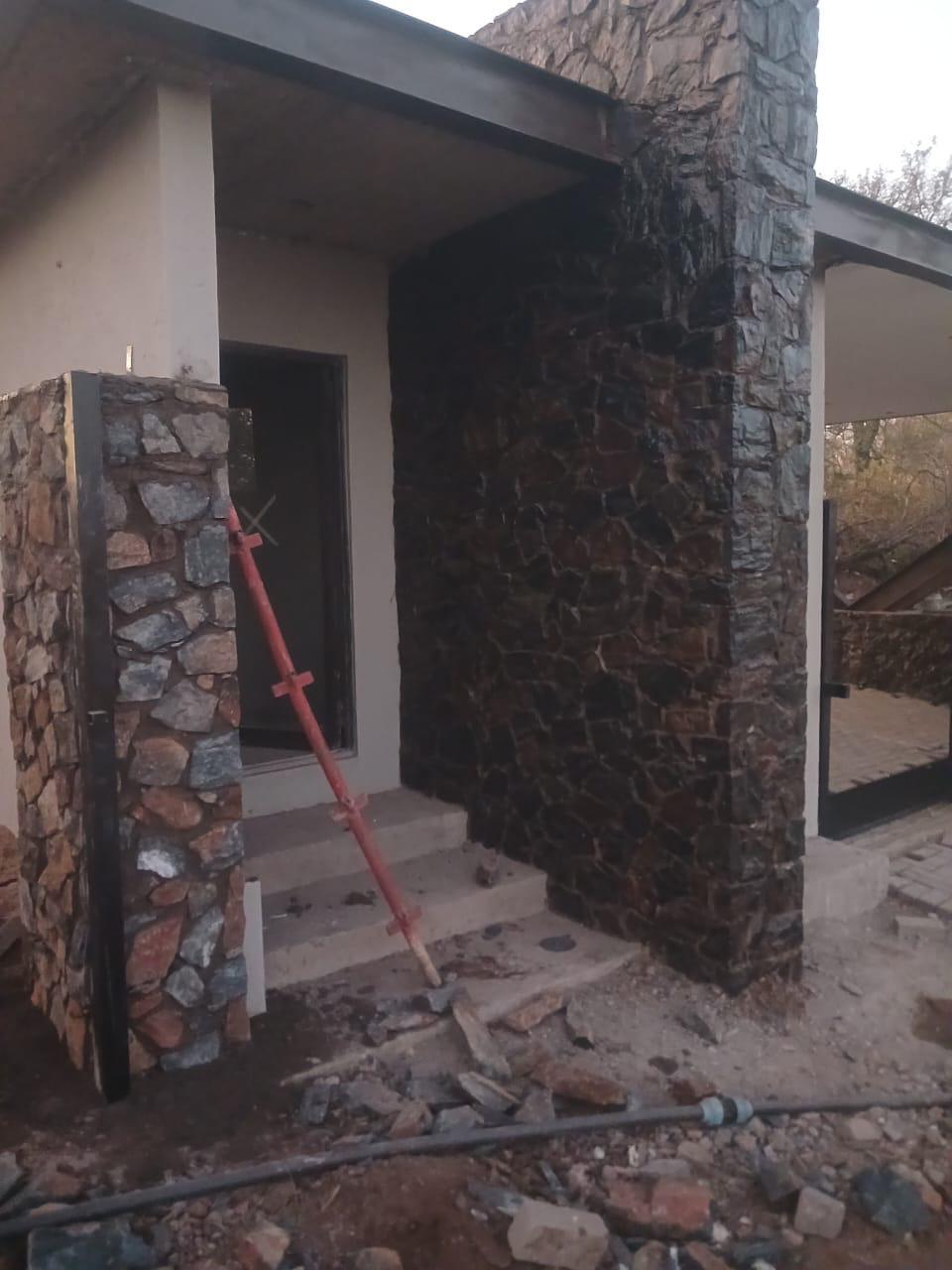 Stone finishes around entrance columns and steps during installation.