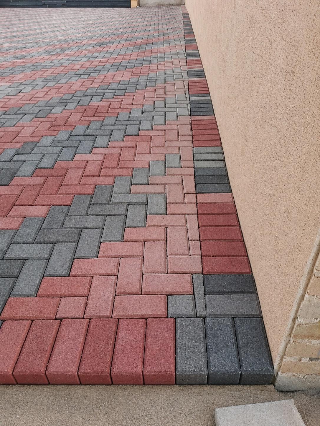 Red and grey interlocking pavers arranged in a patterned walkway.