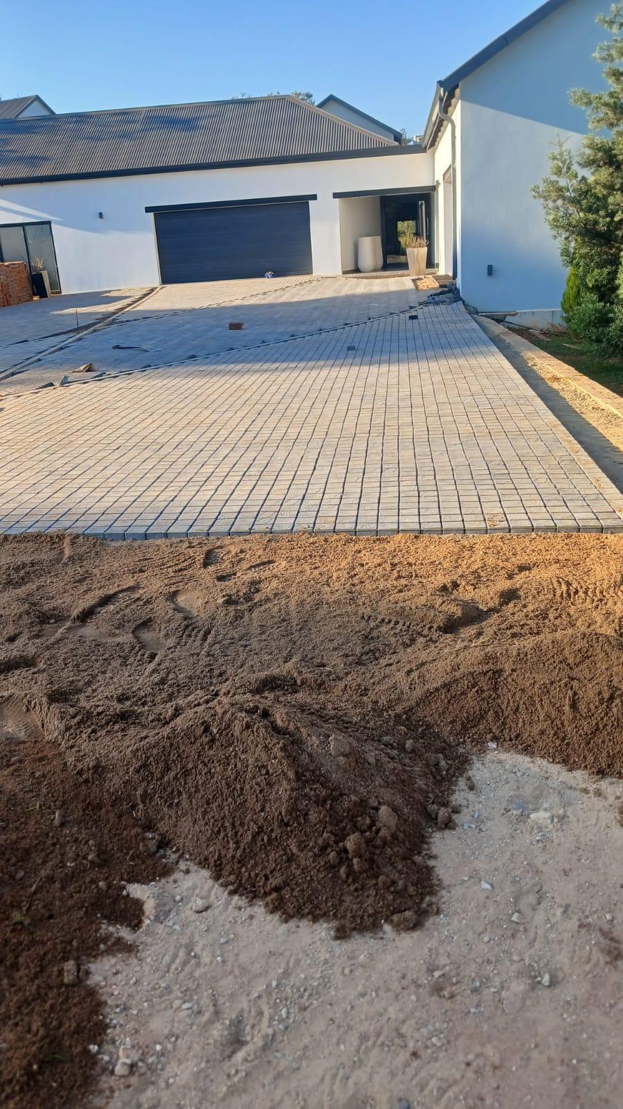 Interlocking driveway paving with adjoining ground preparation at a residential property.